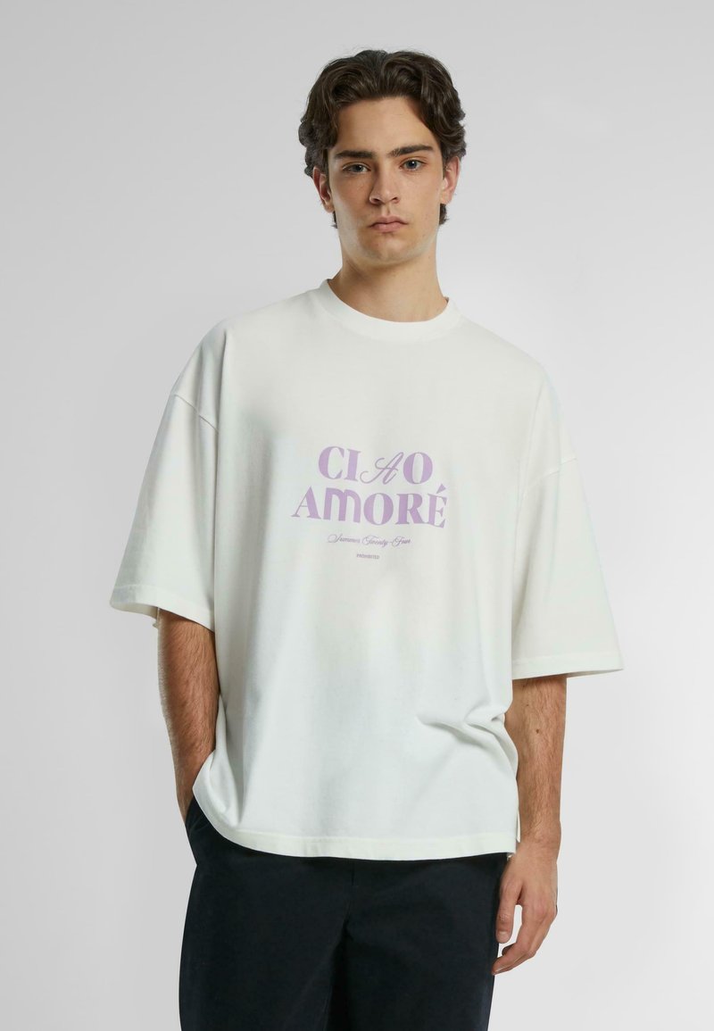 Overdimensjonert hvit bomulls t-skjorte med kort erm som har lys lilla grafisk tekst "CIAO AMORE" sentrert på fronten. Uformell design.