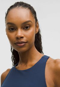 Navy blue sleeveless top with a smooth texture and rounded neckline. Positioned against a neutral background, showcasing a subtle sheen.