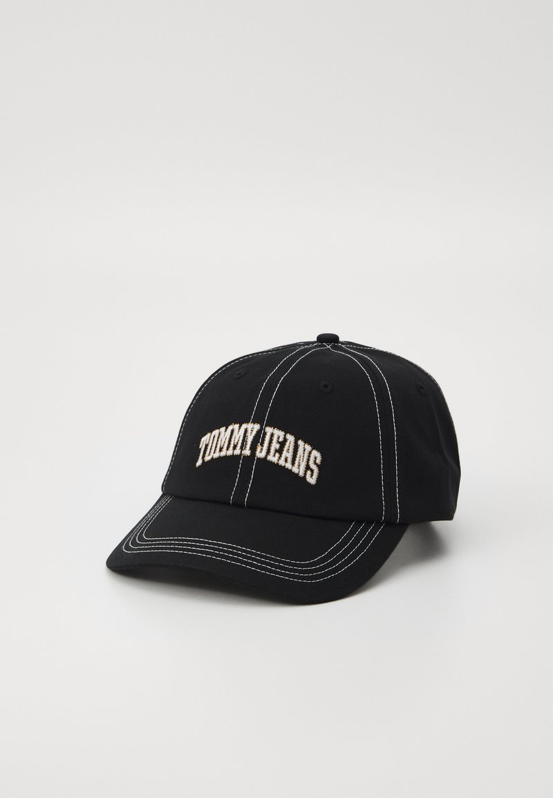 Black cap made of fabric with white stitching. Features an embroidered "TOMMY JEANS" logo on the front in beige. Curved brim design.