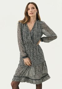 Rochie midi cu model floral, cu mâneci lungi din material transparent, decolteu în V și talie strânsă. Dispune de un tiv volanat și detalii contrastante negre.