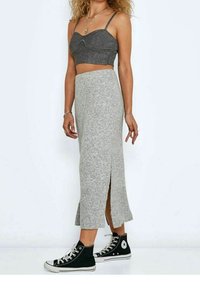Jupe en tricot côtelé gris avec fentes sur les côtés ; associée à un crop top noir et des baskets montantes noires. Tous les objets sur un fond blanc.