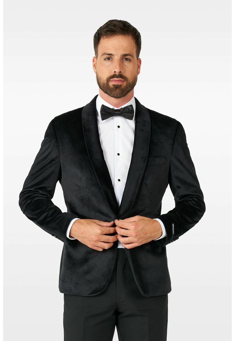 Črn žametni smoking z satenskimi reverji, z enotnim gumbom in sprednjimi žepi, oblečen preko bele srajce in metuljčka.
