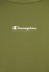 Tessuto verde oliva con il logo "Champion" bianco stampato al centro, che mostra la caratteristica scrittura e il simbolo del marchio.