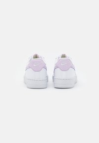Tenisky Nike Air s převážně bílým svrškem, doplněné světle fialovými patkami a texturovanými podrážkami. Mají polstrovaný límec a logo.