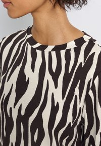 Mustavalkoiset zebra-raidalliset hupparit, jotka on valmistettu pehmeästä puuvillasta, joissa on pyöreä pääntie ja lyhyet hihat, rento malli.