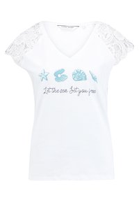 Bílý tričko s véčkovým výstřihem, krajkovými krátkými rukávy a potiskem v mořském tématu v modré barvě, včetně mušlí a hvězdice, s nápisem "Nechte moře, aby vás osvobodilo."