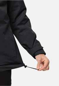 Zwarte waterdichte jas met een trekkoord aan de onderrand. De mouwen zijn voorzien van een manchetontwerp, dat een gladde, matte textuur toont.