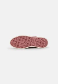 Shoe sole in light pink rubber with a textured pattern, featuring a round emblem and a size indicator marked "37." White outer rim.