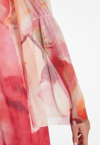 Leichtes, durchsichtiges Kleid mit bunten, abstrahierten Mustern in Pink, Rot und Pfirsich. Verfügt über lockere, geraffte Ärmel und eine glatte Textur.
