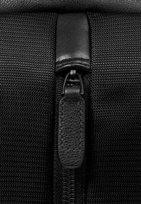 Tessuto nero testurizzato con cerniera a strappo in pelle. La cerniera offre una scorrevolezza fluida ed è rinforzata con cuciture robuste.