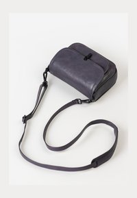 Borsa a tracolla in pelle viola con una texture liscia, chiusura con zip e tracolla regolabile; presenta bordi arrotondati e due tasche frontali.