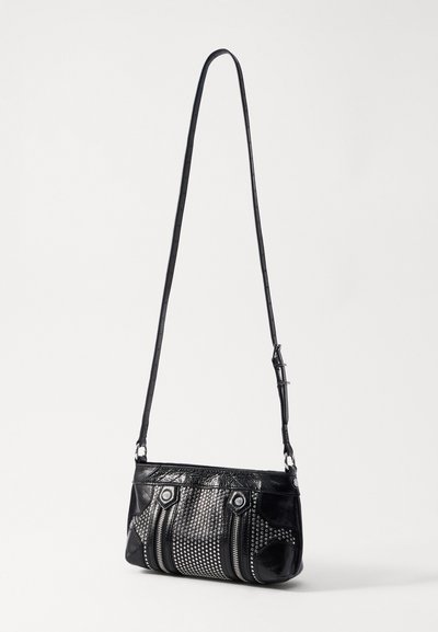 Black leather handbag with a smooth texture, accented by silver studs and zippers, featuring a long adjustable strap.