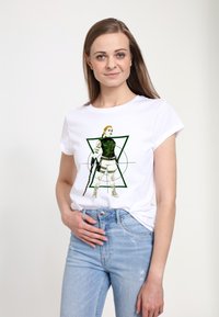 Bílý tričko s grafikou postavy v zeleném taktickém vybavení, která drží zbraň, na pozadí geometrického zeleného designu.