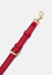 Červený kožený pásek s pozlacenými detaily, nastavitelnou přezkou a klipovým upevněním. Hladká textura s prošívanými detaily.