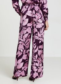 Pantalons à jambes larges en tissu lisse avec un fond violet foncé ornés de grands motifs floraux roses et une taille élastique.
