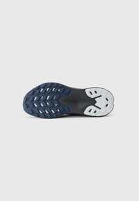 Semelle de chaussure en caoutchouc avec un motif de bande de roulement multidirectionnel, principalement marine avec des accents blancs, présentant une surface texturée pour une meilleure adhérence.