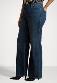 High-waisted, wide-leg blue denim jeans with a button fly, featuring classic five-pocket styling and a slightly faded texture.