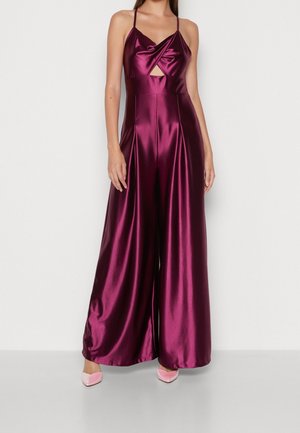 Bordowy jedwabisty kombinezon z satyny z dekoltem halter, skręconym przodem i wycięciem w talii; szerokie nogawki opadające od talii.
