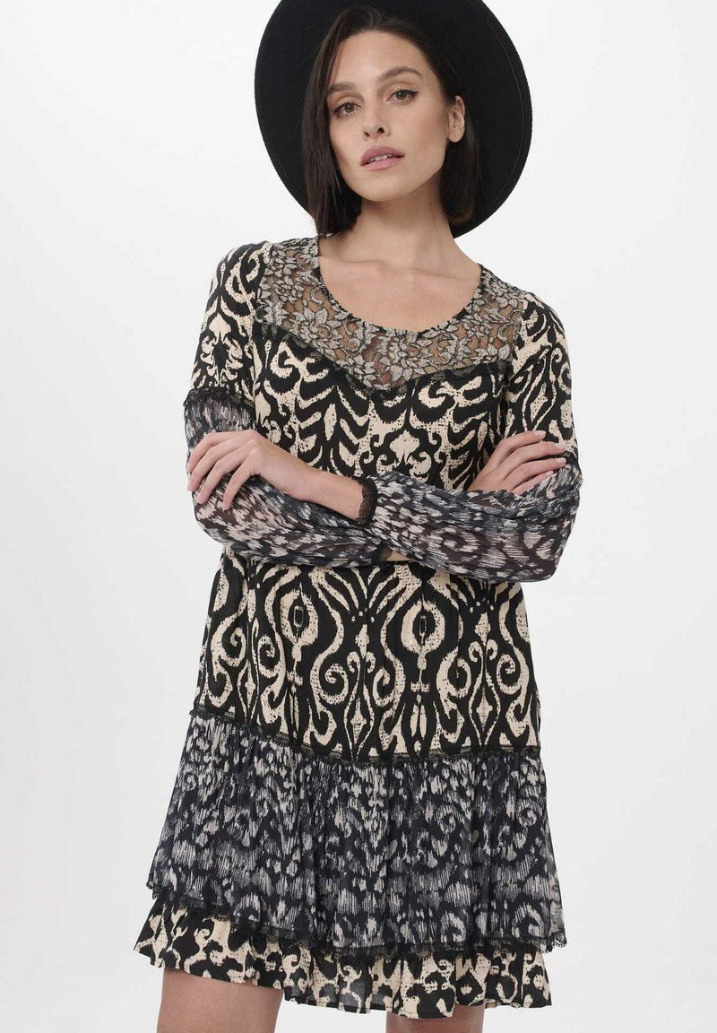 Schwarz-creamfarbenes Kleid mit gemustertem Design, Spitzen-Ausschnitt, langen Ärmeln und gestuften Rüschen. Verfügt über aufwendige Motive und eine fließende Stofftextur.