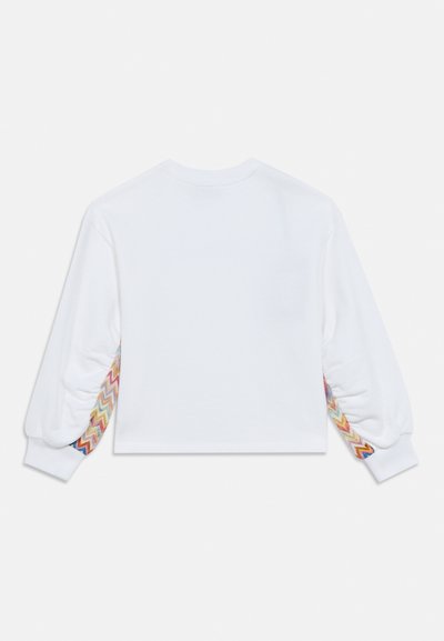 Λευκό cropped φούτερ με μακριά μανίκια, με πολύχρωμες ζιγκ-ζαγκ λεπτομέρειες στις μανσέτες. Μαλακό ύφασμα και άνετη εφαρμογή.