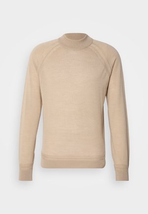 Beige trikåtröja med ribbad hög hals, långa ärmar och raglanärmsöm, tillverkad av ett slätt material. Enkel, ren design.