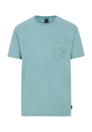 Camiseta de algodón azul claro con cuello redondo, mangas cortas y un bolsillo frontal que presenta un diseño de logo impreso. Textura suave.