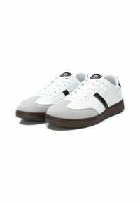 Zapatillas deportivas en blanco y gris, fabricadas con materiales de ante y sintéticos, que cuentan con una franja negra, punta redonda y suela de goma. Los cordones son blancos.