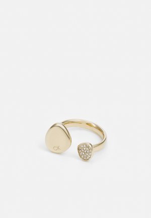Gold-tone ring with two abstract shapes; one smooth with "CK" engraving, the other encrusted with clear stones.