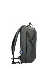 Sac à dos noir avec une finition lisse et texturée, des bretelles rembourrées et des sangles de compression latérales. Comprend un matériel ajustable pour un maintien sécurisé.