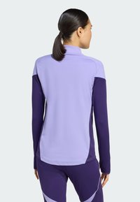 Light purple long-sleeve top with darker purple accents, featuring a high collar and smooth, stretchy fabric for comfort and fit.