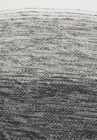 Strickstoff mit einem Farbverlauf, der von Weiß zu Schwarz übergeht, mit strukturierten, erhabenen Stichen in unterschiedlichen Dicken.