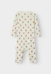 Långärmad babyromper i off-white tyg med små bruna nallebjörnar. Mjuk textur och tryckknappar i halsen för enkel påklädning.