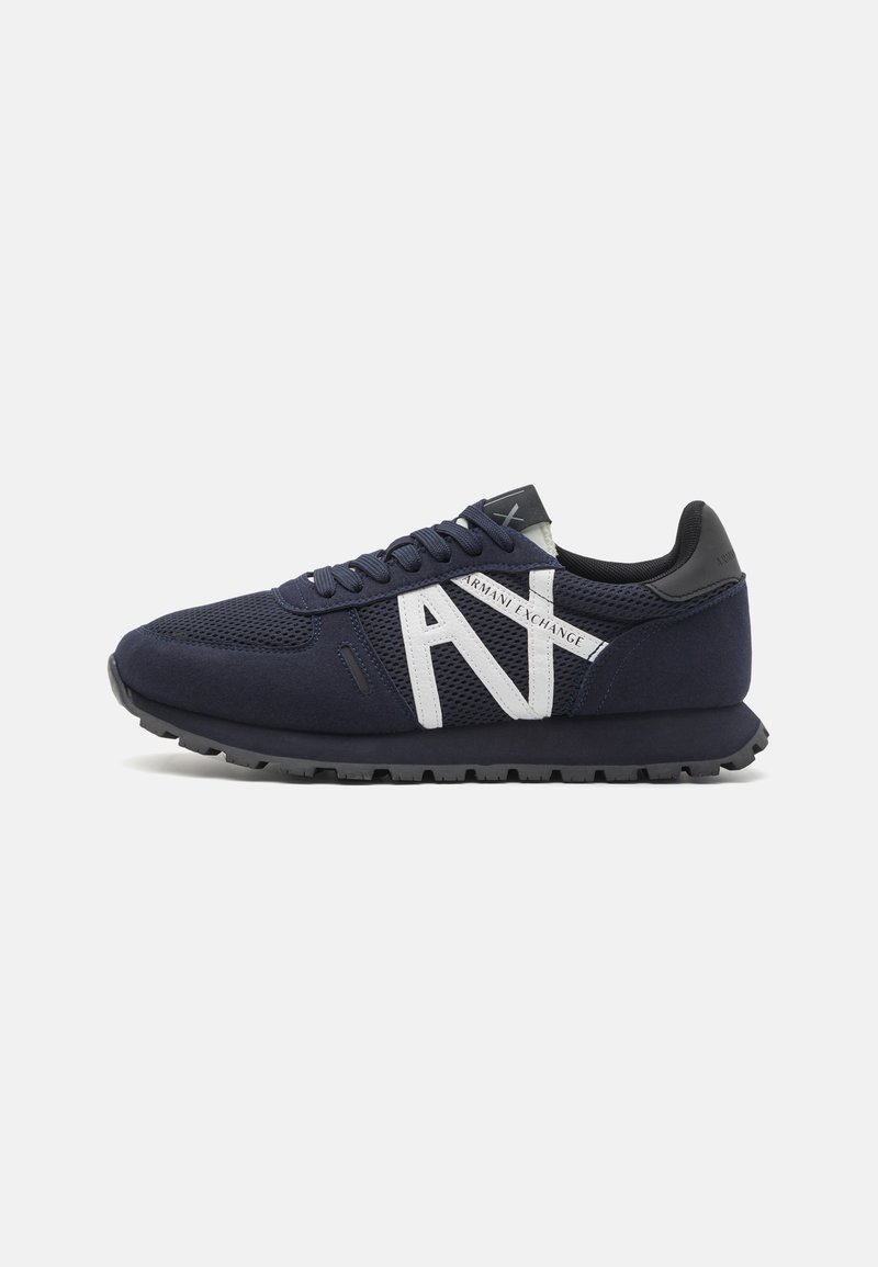Sneaker bleu marine en matériau mesh et daim, présentant un grand logo "A" blanc, une semelle texturée et des accents noirs sur le talon et la languette.