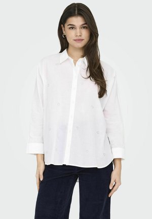 White linen shirt with a button-front, long sleeves, and small embroidered heart patterns. Soft texture and a relaxed fit.