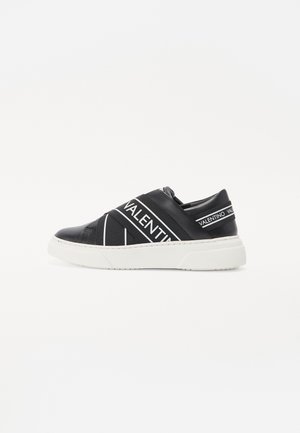 Svart slip-on sneakers med hvite dekorative stropper som har "VALENTINO"-tekst. Hvit gummisåle, glatt overmateriale og diagonalstripet design.