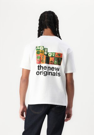 White cotton t-shirt featuring a colorful graphic of speakers on the back, with black text reading "the new originals" underneath.