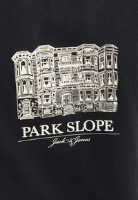 Camiseta negra con una ilustración en blanco de un edificio de varios pisos con balcones. Texto "PARK SLOPE" y "Jack & Jones" debajo.