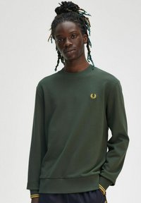 Felpa verde con girocollo, polsini e orlo a coste. Presenta un piccolo logo dorato sul petto e dettagli a strisce gialle sulle maniche.