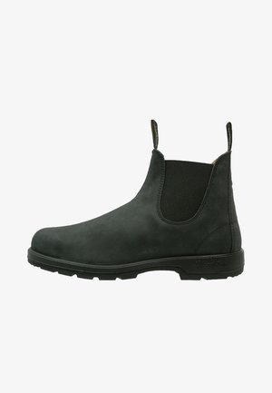 Zwarte Chelsea-boots van suède, met elastische zijpanelen en een textuurrubberen zool. Ronde neus met aantrek-lussen voor gemakkelijk aantrekken.