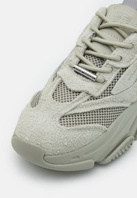 Sneaker verde chiaro caratterizzata da una combinazione di materiali in suede e mesh, tomaia testurizzata, chiusura con lacci e dettagli del logo argentato sulla linguetta.