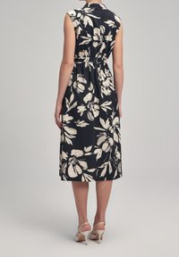 Floral-printed dress with a dark navy background, sleeveless design, cinched waist, and knee-length cut. Accented with light-colored flowers.