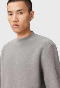 Szary sweatshirt z okrągłym dekoltem, wykonany z teksturowanej tkaniny. Posiada obniżone ramiona oraz ściągacz przy dekolcie. Prosty, minimalistyczny design.