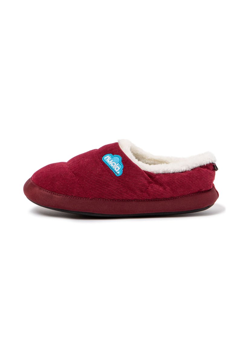 Zapatilla de corduroy roja con un suave forro blanco, textura acolchada y un logo azul. Diseño de tipo slip-on con una suela de goma flexible.