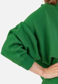 Pull vert surdimensionné doté d'une coupe ample, d'un tissu texturé et de manches larges. L'ourlet présente une finition côtelée douce pour plus de confort.