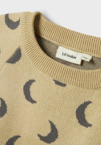 Beige Pullover mit grauen Halbmondmustern, einem gerippten Halsauschnitt und einem sichtbaren Markenlabel "Lil'Atelier" im Kragen.