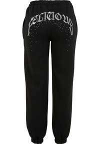 Black sweatpants with an elastic waistband, featuring white 'FOLICIOUS' text and embellishments on the back, tapered cuffs, and side pockets.