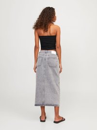 Svart stroppeløs topp, lys grå høy midje denim maxiskjørt med to baklommer og rett silhuett. Brukt med svarte sandaler.