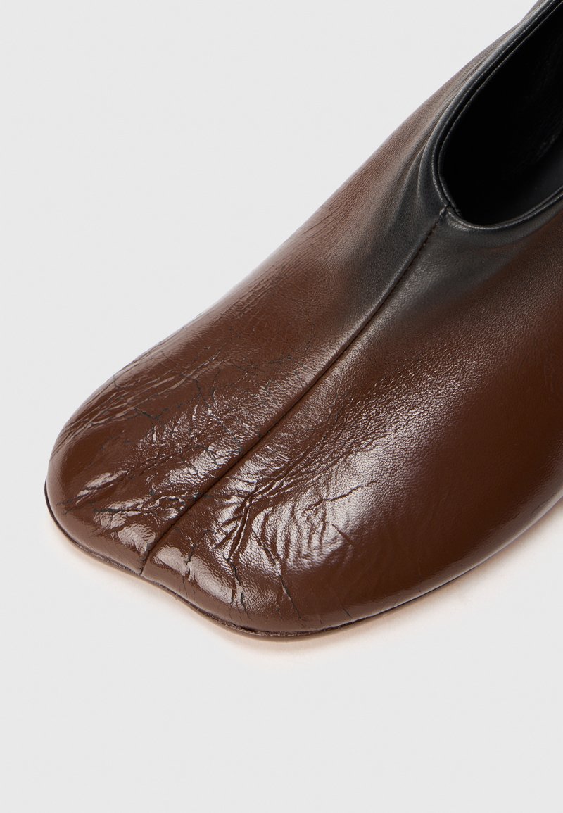 Scarpa in pelle marrone con punta quadrata e cucitura centrale, con una texture liscia e leggermente rugosa.