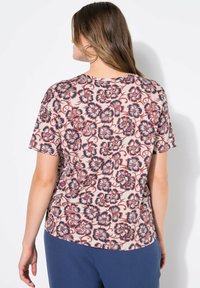 Kurzärmliges Hemd mit floralem Muster in Marineblau und Rot auf beigem Hintergrund. Weicher Stoff mit entspannter Passform und abgerundetem Saum.