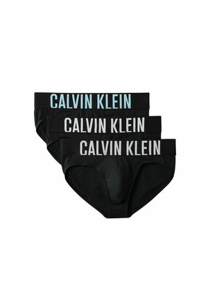 Tre slip neri da uomo con ampie fasce in vita, ciascuno con il logo Calvin Klein in grandi lettere bianche o azzurro chiaro.
